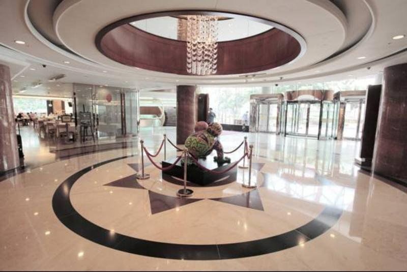 Evergreen Laurel Hotel - Tchaj-čung Exteriér fotografie The photo depicts an elegant indoor space, likely the lobby of a hotel or a building. The flooring is made of polished marble tiles, featuring a circular design with contrasting black and light-colored sections. At the center, there is a sculpture su