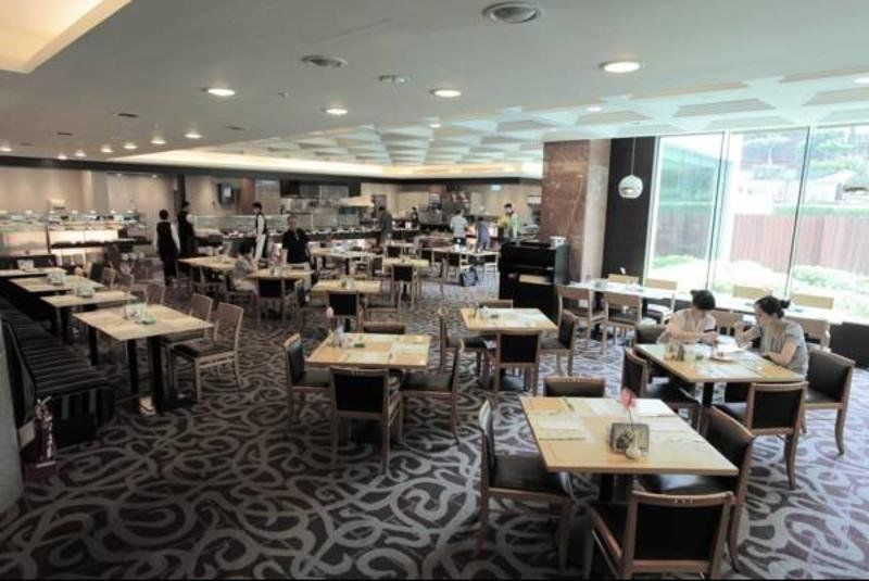 Evergreen Laurel Hotel - Tchaj-čung Exteriér fotografie The photo shows a spacious restaurant or dining area with a modern interior design. There are several tables arranged throughout the room, some of which are set for dining while others appear to be empty. The decor includes a patterned carpet and lar