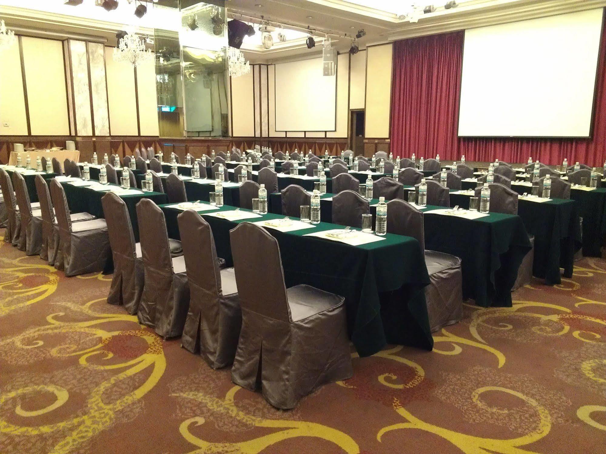 Evergreen Laurel Hotel - Tchaj-čung Exteriér fotografie The photo shows a large conference or meeting room set up with multiple tables arranged in a structured manner. Each table is covered with a tablecloth, alternating between black and green. There are chairs around each table, and each place setting a