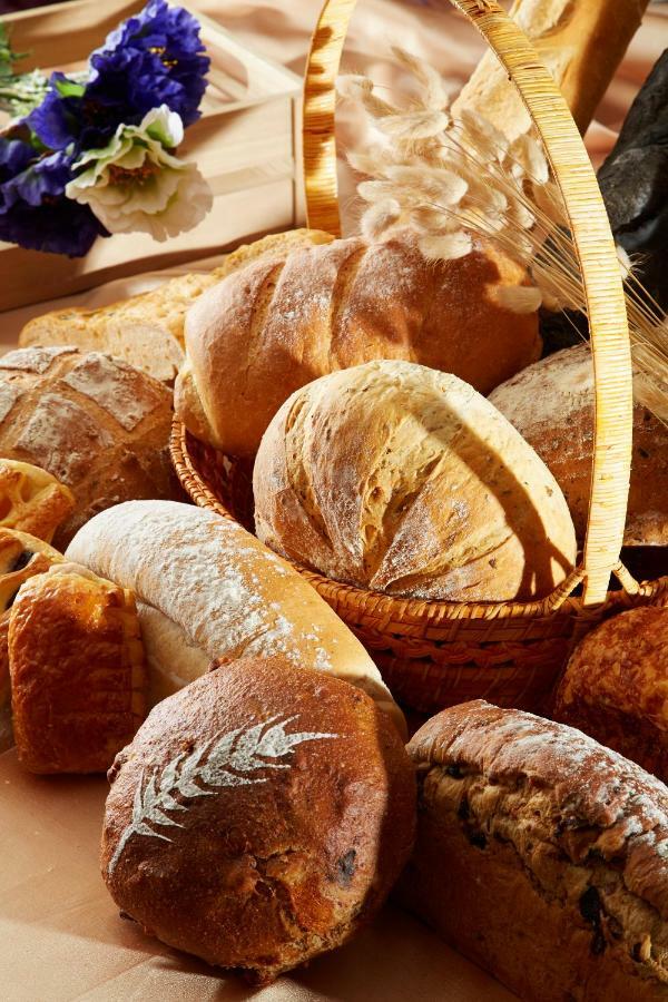 Evergreen Laurel Hotel - Tchaj-čung Exteriér fotografie The photo shows a variety of freshly baked bread arranged in a woven basket. There are different types of bread, including round loaves, baguettes, and crusty rolls, showcasing a range of colors and textures. Some loaves have distinctive patterns or 