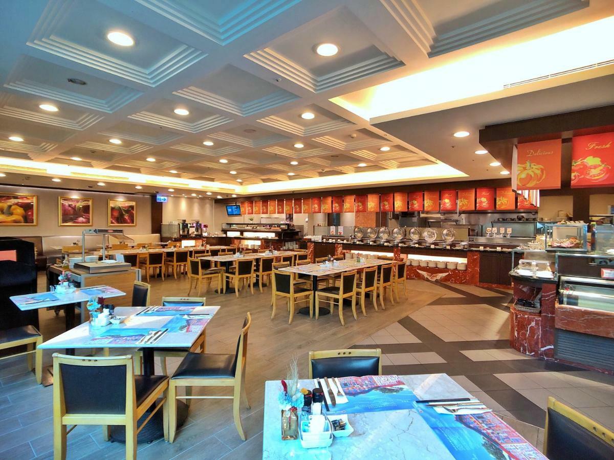 Evergreen Laurel Hotel - Tchaj-čung Exteriér fotografie The photo shows the interior of a restaurant. The dining area features several tables with chairs arranged neatly. The flooring has a contemporary design, and the ceiling is structured with a coffered pattern. There is a buffet area along one wall wi