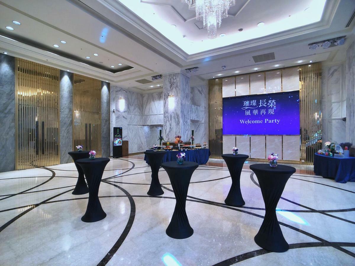 Evergreen Laurel Hotel - Tchaj-čung Exteriér fotografie The photo depicts a spacious and elegantly decorated event space, likely set up for a welcome party. The room features polished marble flooring and tall ceilings, giving it a sophisticated atmosphere. In the center, several round tables with black ta