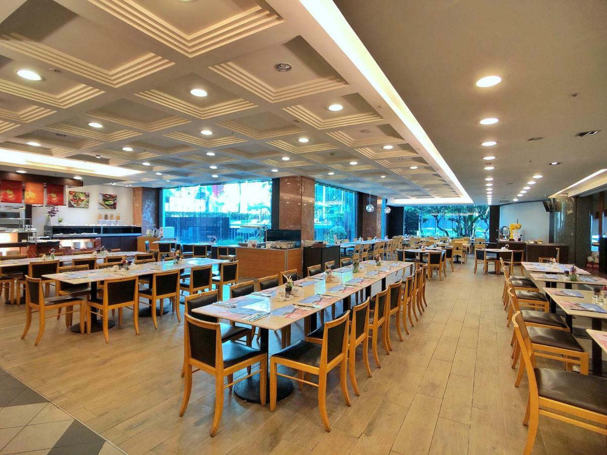 Evergreen Laurel Hotel - Tchaj-čung Exteriér fotografie The photo shows the interior of a restaurant. It features a spacious dining area with several wooden tables and chairs arranged in rows. The floor has a light wood finish, complementing the stylish design. The ceiling is decorated with a modern patte