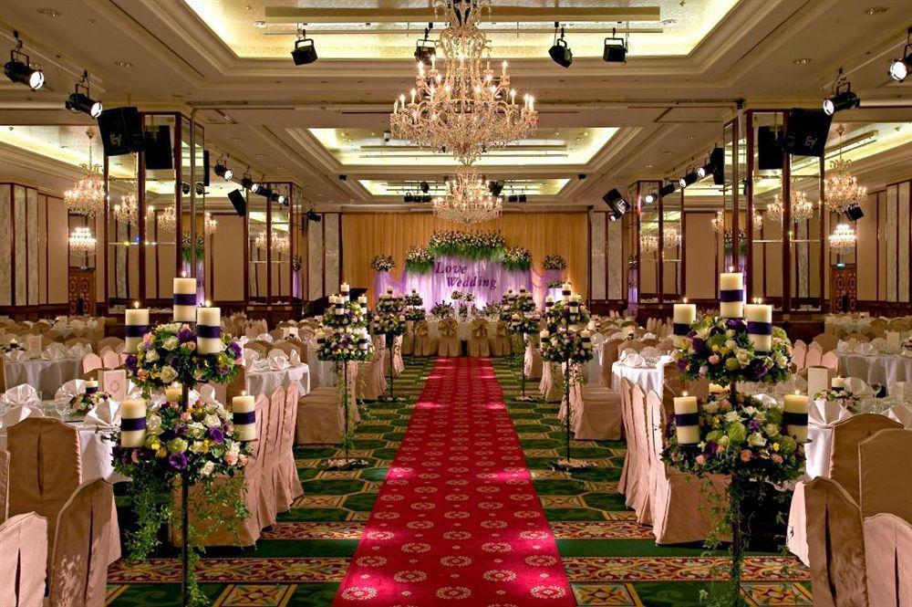 Evergreen Laurel Hotel - Tchaj-čung Exteriér fotografie The photo shows an elegantly decorated banquet hall set up for a wedding or formal event. The center aisle is lined with rows of elegantly draped chairs and features a bright red carpet. On either side of the aisle, there are beautifully arranged flo