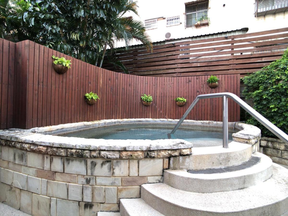 Evergreen Laurel Hotel - Tchaj-čung Exteriér fotografie The photo shows a small outdoor hot tub or spa area. It's surrounded by a wooden fence, with several planters containing greenery attached to the wall. The hot tub is round, with a stone border, and there are steps leading up to it with a stainless s